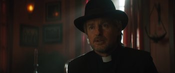 Movie still from “Haunted Mansion” (2023), directed by Justin Simien – A man wearing a black hat and a priest's outfit; Close Up shot, Low angle