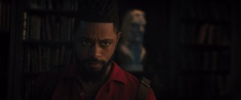 Movie still from “Haunted Mansion” (2023), directed by Justin Simien – A person wearing a red shirt with a statue in the background; Close Up shot, Over the shoulder angle
