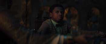 Movie still from “Haunted Mansion” (2023), directed by Justin Simien – A young man wearing a bow tie sitting at a table; Close Up shot, Over the shoulder angle