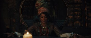 Movie still from “Haunted Mansion” (2023), directed by Justin Simien – A woman sitting in front of a lit candle; Medium shot, Over the shoulder angle