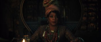 Movie still from “Haunted Mansion” (2023), directed by Justin Simien – A woman sitting on top of a couch wearing a turban; Close Up shot, Over the shoulder angle
