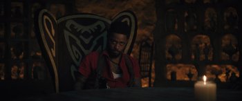 Movie still from “Haunted Mansion” (2023), directed by Justin Simien – A man sitting at a table in a room; Medium shot, Over the shoulder angle