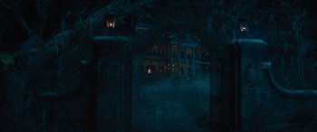 Movie still from “Haunted Mansion” (2023), directed by Justin Simien – An old mansion is seen through a gate at night; Extreme Wide shot, High angle