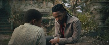 Movie still from “Haunted Mansion” (2023), directed by Justin Simien – A man sitting on the ground with another man; Close Up shot, Over the shoulder angle