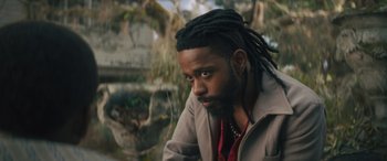 Movie still from “Haunted Mansion” (2023), directed by Justin Simien – A person with dreads looking at the camera; Close Up shot, Low angle