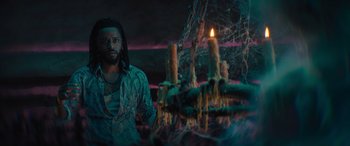 Movie still from “Haunted Mansion” (2023), directed by Justin Simien – A man standing in front of a lit candle; Medium shot, Low angle