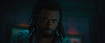 Movie still from “Haunted Mansion” (2023), directed by Justin Simien – A person with dreadlocks looking at the camera; Close Up shot, Low angle