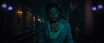 Movie still from “Haunted Mansion” (2023), directed by Justin Simien – A man with dreads is standing in a dark room; Close Up shot, Low angle
