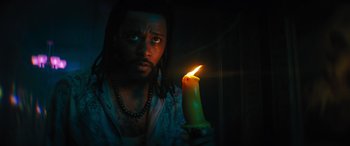 Movie still from “Haunted Mansion” (2023), directed by Justin Simien – A man holding a lit candle in a dark room; Close Up shot, Low angle
