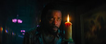 Movie still from “Haunted Mansion” (2023), directed by Justin Simien – A man with dreadlocks holding a lit candle in front of his face; Close Up shot, Low angle