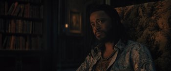 Movie still from “Haunted Mansion” (2023), directed by Justin Simien – A man with dreadlocks sitting in a room; Close Up shot, Over the shoulder angle