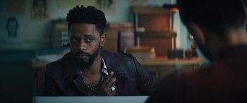 Movie still from “Haunted Mansion” (2023), directed by Justin Simien – A man sitting in front of a table with other people; Close Up shot, Over the shoulder angle