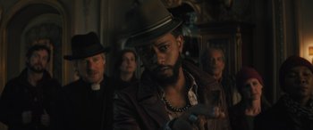 Movie still from “Haunted Mansion” (2023), directed by Justin Simien – A group of people standing in a room; Close Up shot, Over the shoulder angle