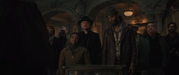 Movie still from “Haunted Mansion” (2023), directed by Justin Simien – A group of people standing around a table; Medium shot, Low angle