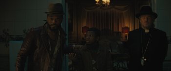 Movie still from “Haunted Mansion” (2023), directed by Justin Simien – A man and a boy are standing in a living room; Medium shot, Over the shoulder angle