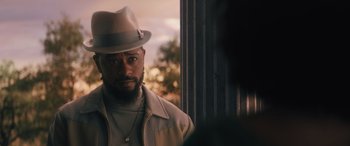 Movie still from “Haunted Mansion” (2023), directed by Justin Simien – A man wearing a hat and a jacket looking out a window; Close Up shot, Over the shoulder angle
