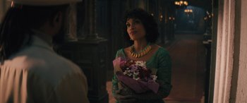 Movie still from “Haunted Mansion” (2023), directed by Justin Simien – A woman holding a bouquet of flowers while wearing a necklace; Medium shot, Over the shoulder angle