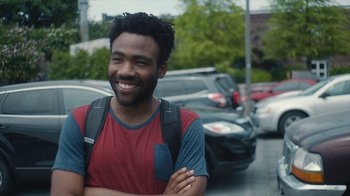 Movie still from “Atlanta” (2016), created by Donald Glover – A man with a backpack standing on the side of the road; Close Up shot, Over the shoulder angle