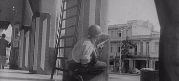 Movie still from “Hawking: Can You Hear Me?” (2021), directed by Oliver Twinch – An old photo of a man holding a rifle; Medium shot, Low angle