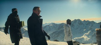Movie still from “Heart of Stone” (2023), directed by Tom Harper – A man and a woman standing on top of a snow covered slope; Medium shot, Low angle