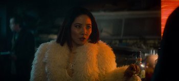 Movie still from “Heart of Stone” (2023), directed by Tom Harper – A woman in a white fur coat looking at the camera; Close Up shot, Over the shoulder angle