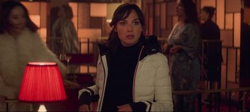 Movie still from “Heart of Stone” (2023), directed by Tom Harper – A woman in a white jacket standing in a room; Medium shot, Over the shoulder angle