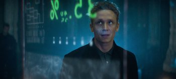 Movie still from “Heart of Stone” (2023), directed by Tom Harper – A man standing in front of a glass window; Close Up shot, Low angle