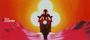 Movie still from “Heart of Stone” (2023), directed by Tom Harper – A person on a red motorcycle in front of an orange background; Extreme Wide shot, Low angle