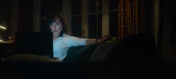 Movie still from “Heart of Stone” (2023), directed by Tom Harper – A woman sitting on top of a couch with a computer; Medium shot, High angle