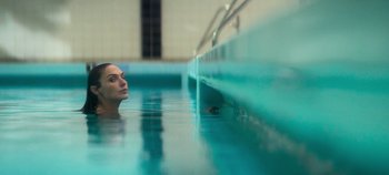 Movie still from “Heart of Stone” (2023), directed by Tom Harper – A woman in a swimming pool with her head above the water; Close Up shot, Over the shoulder angle