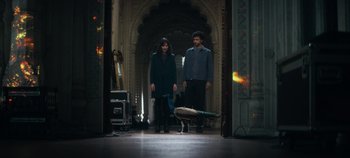 Movie still from “Heart of Stone” (2023), directed by Tom Harper – A man and a woman standing next to a peacock; Wide shot, High angle