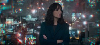 Movie still from “Heart of Stone” (2023), directed by Tom Harper – A woman standing in front of a city at night with her arms crossed; Medium shot, Over the shoulder angle