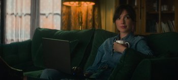 Movie still from “Heart of Stone” (2023), directed by Tom Harper – A woman sitting on a couch with a laptop; Medium shot, Over the shoulder angle