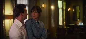Movie still from “Heart of Stone” (2023), directed by Tom Harper – A man and a woman sitting next to each other in a room; Medium shot, Over the shoulder angle