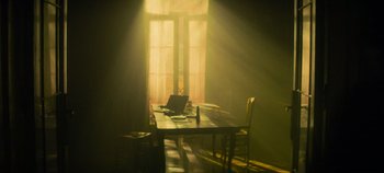 Movie still from “Heart of Stone” (2023), directed by Tom Harper – A table and chairs in a room lit by a window; Wide shot, Low angle