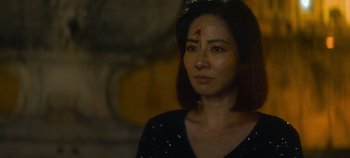 Movie still from “Heart of Stone” (2023), directed by Tom Harper – A woman wearing a black shirt with a red cross on her forehead; Close Up shot, High angle