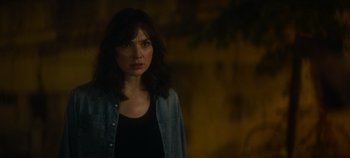 Movie still from “Heart of Stone” (2023), directed by Tom Harper – A woman standing in a dark room with her head turned to the side; Close Up shot, Over the shoulder angle