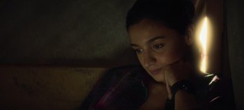 Movie still from “Heart of Stone” (2023), directed by Tom Harper – A woman sitting on a couch in a dark room; Close Up shot, High angle