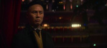 Movie still from “Heart of Stone” (2023), directed by Tom Harper – A man standing in front of an audience at a theater; Medium shot, Low angle