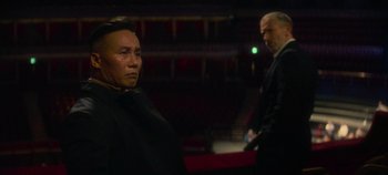 Movie still from “Heart of Stone” (2023), directed by Tom Harper – A man in a black suit standing next to another man in a black suit; Medium shot, Low angle