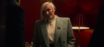 Movie still from “Heart of Stone” (2023), directed by Tom Harper – An older man with white hair wearing a suit; Medium shot, Over the shoulder angle