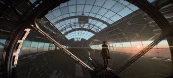 Movie still from “Heart of Stone” (2023), directed by Tom Harper – A man standing in a train station with a camera; Extreme Wide shot, Low angle