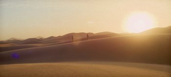 Movie still from “Heart of Stone” (2023), directed by Tom Harper – A couple of people standing on top of a sand dune; Extreme Wide shot, High angle