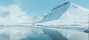 Movie still from “Heart of Stone” (2023), directed by Tom Harper – A view of a snowy mountain and a body of water; Extreme Wide shot, Low angle