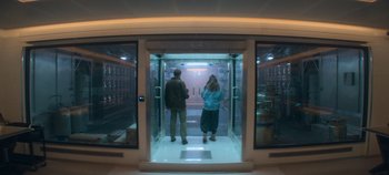 Movie still from “Heart of Stone” (2023), directed by Tom Harper – A man and a woman standing inside of an elevator; Wide shot, Low angle
