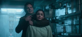 Movie still from “Heart of Stone” (2023), directed by Tom Harper – A man and a woman holding a gun in a room; Medium shot, Low angle