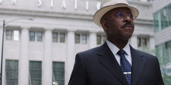 Movie still from “Heist 88” (2023), directed by Menhaj Huda – A man in a suit and a white hat; Close Up shot, Low angle