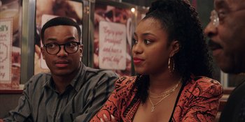 Movie still from “Heist 88” (2023), directed by Menhaj Huda – A man and a woman sitting next to each other; Close Up shot, Over the shoulder angle