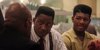 Movie still from “Heist 88” (2023), directed by Menhaj Huda – A man in a striped shirt and a red tie; Close Up shot, Over the shoulder angle