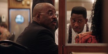 Movie still from “Heist 88” (2023), directed by Menhaj Huda – Two men are looking at each other in a mirror; Close Up shot, Over the shoulder angle